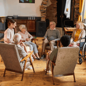 A group of elderly people and a caregiver sitting in a circle, representing the community and care within a nursing home or senior living facility.