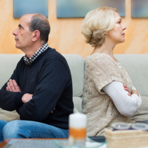 Estranged adult siblings sitting back-to-back on a couch, illustrating a power of attorney family dispute
